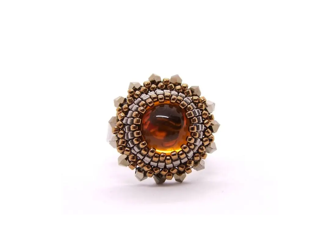 Ring mit bernsteinfarbenen Cabochon umperlt mit 
						Rocailles.